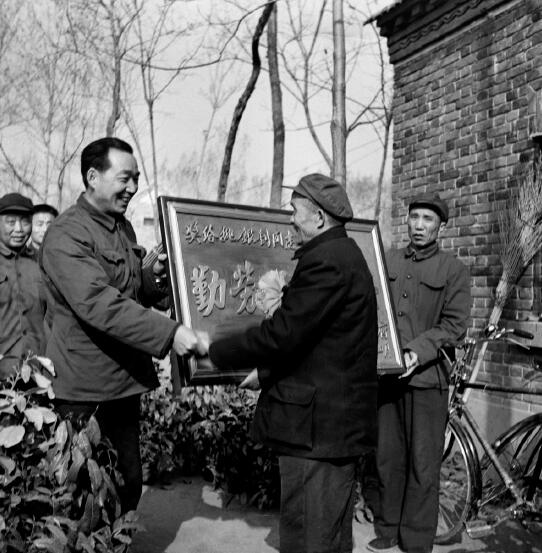 1978年，黨的十一屆三中全會召開，做出了對于當代中國發展具有歷史性影響的重大決策，開啟了改革開放和集中力量進行社會主義現代化建設的歷史新時期。圖為1982年，時任河南省鄢陵縣縣長吳德榮上門為該縣第一個“萬元戶”頒發勞動光榮匾。